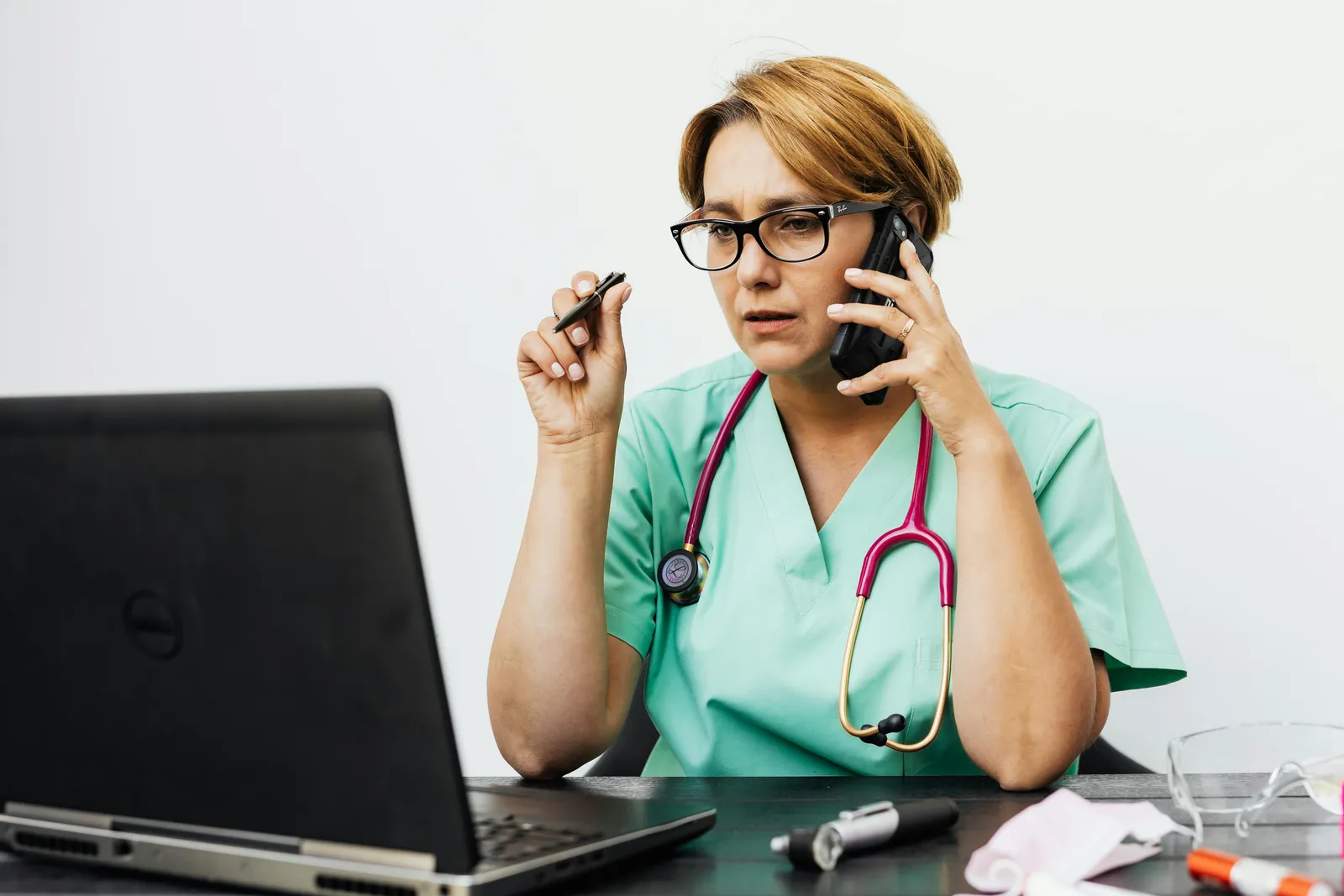 Nurse in scrubs on a phone call at her desk